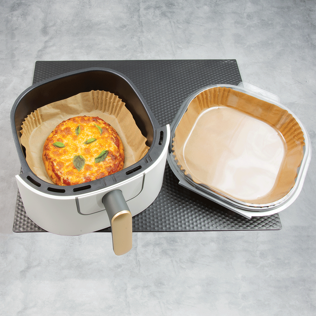 Miniature pizza inside of air fryer liner in air fryer on marble background