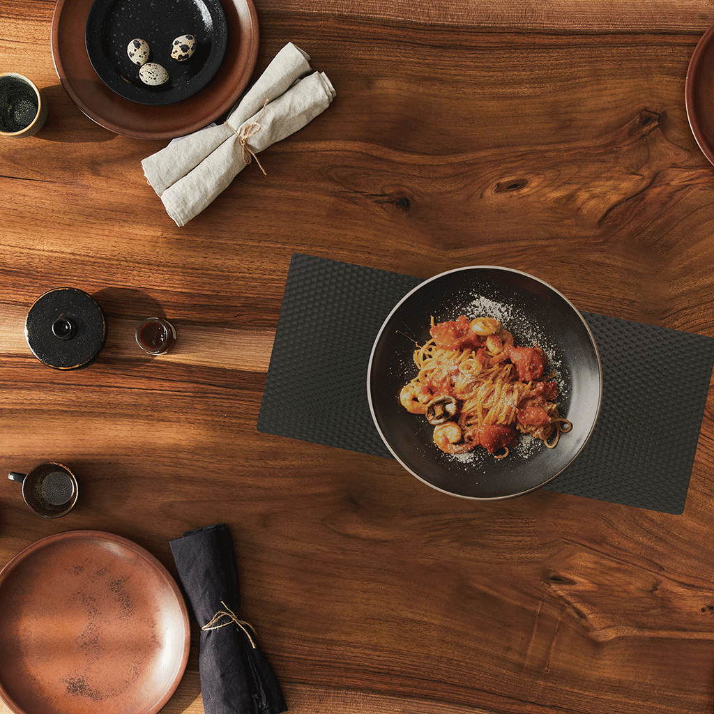 BLack matte counter mat on wooden table with assorted dishes