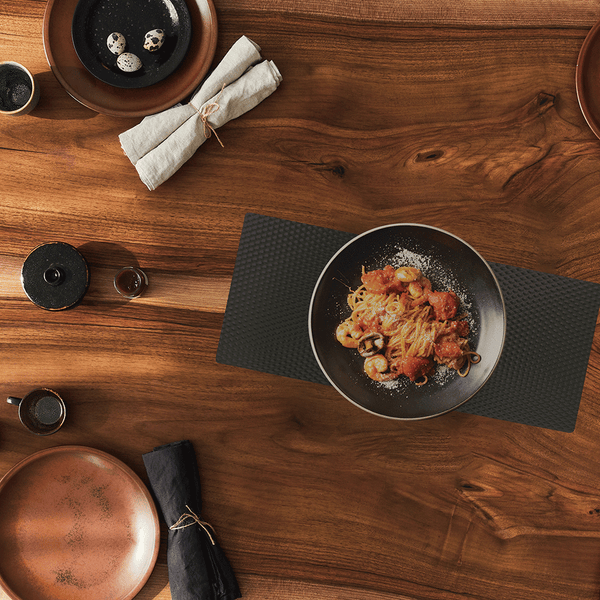 BLack matte counter mat on wooden table with assorted dishes