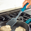 Taste of Home Nylon Slotted Turner with Ash Gray head, Sea Green handle, top view lifting food from pan, lifestyle background