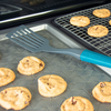 Taste of Home Nylon Slotted Turner with Ash Gray head, Sea Green handle, top view lifting food from pan, on baking sheet surrounded by cookies 