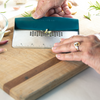 Taste of Home Bench Scraper with Sea Green handle, angled view on cutting board, close up crushing garlic