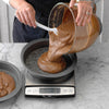 adding cake batter to round baking pan